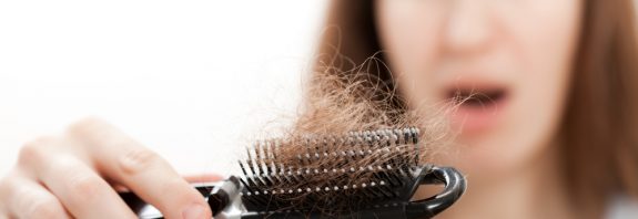 Problem wypadania włosów - zdjęcie kobiecej ręki trzymającej wypadanie włosów grzebieniem — Obraz stockowy